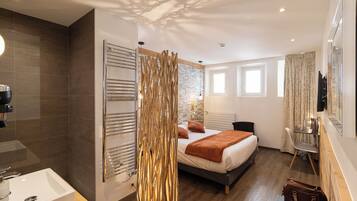 Una habitación de hotel moderna con una cama grande, un baño con lavamanos y un elemento decorativo en la pared.