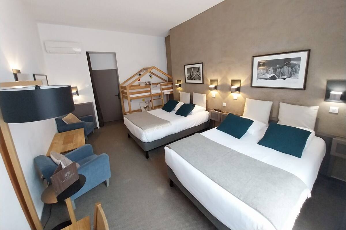A hotel room with two beds, a desk, a chair, and a wardrobe.