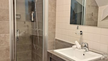 A modern bathroom with a glass-enclosed shower, a white sink, and a large mirror above it.