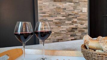A dining table with a charcuterie board, two wine glasses, and a television mounted on a stone wall.