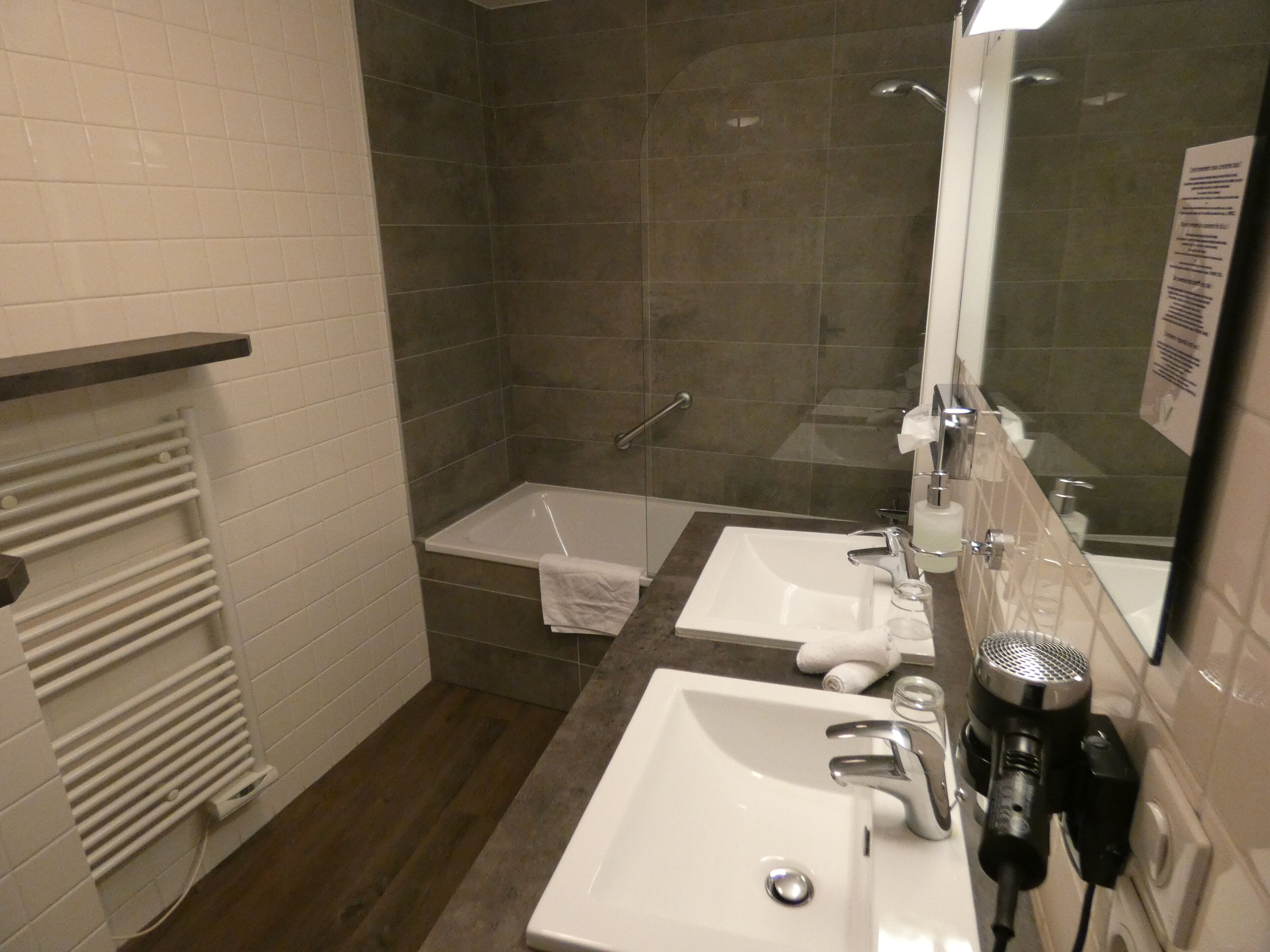 A bathroom with two sinks, a shower, and a towel rack.