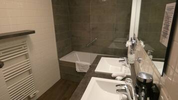A bathroom with two sinks, a shower, and a towel rack.
