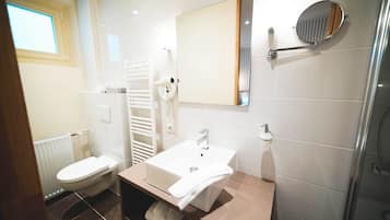Ein modernes Badezimmer mit einem weißen Waschbecken, einem Spiegel, einem Handtuchhalter und einer Toilette.