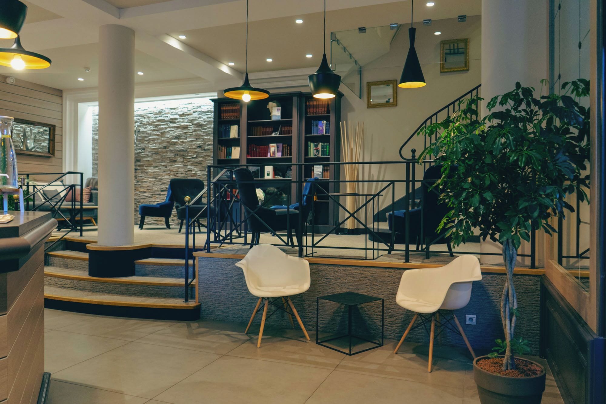 A modern interior with a staircase, seating area, and a bookshelf.