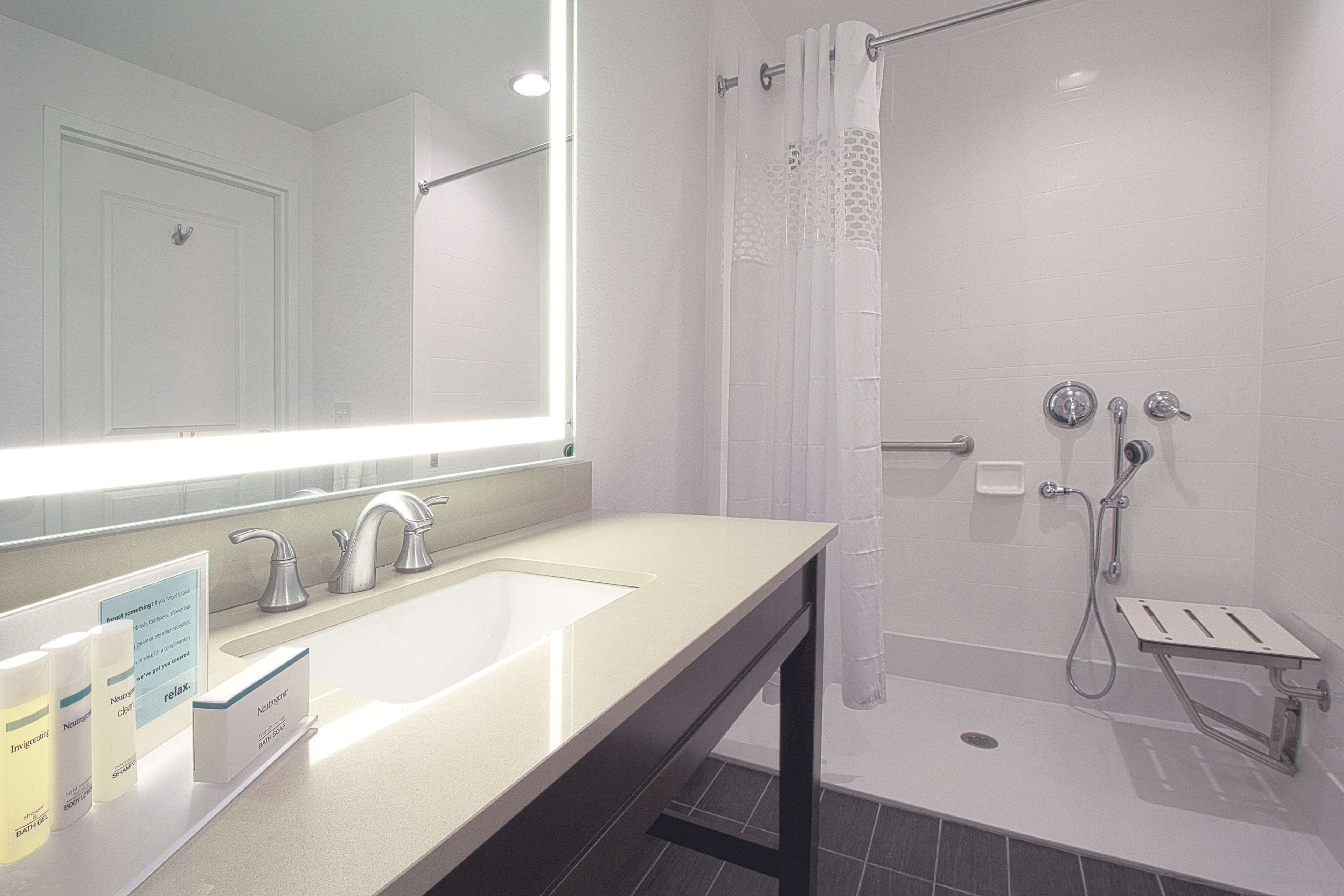 Une salle de bain moderne avec un grand miroir, un lavabo et un espace douche.