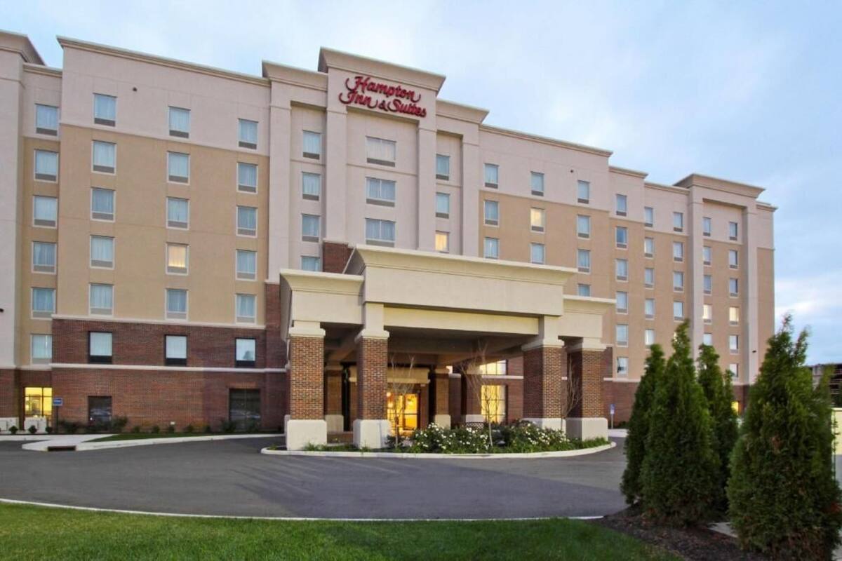 A large, multi-story hotel with a prominent entrance and a sign reading 'Hampton Inn & Suites.'