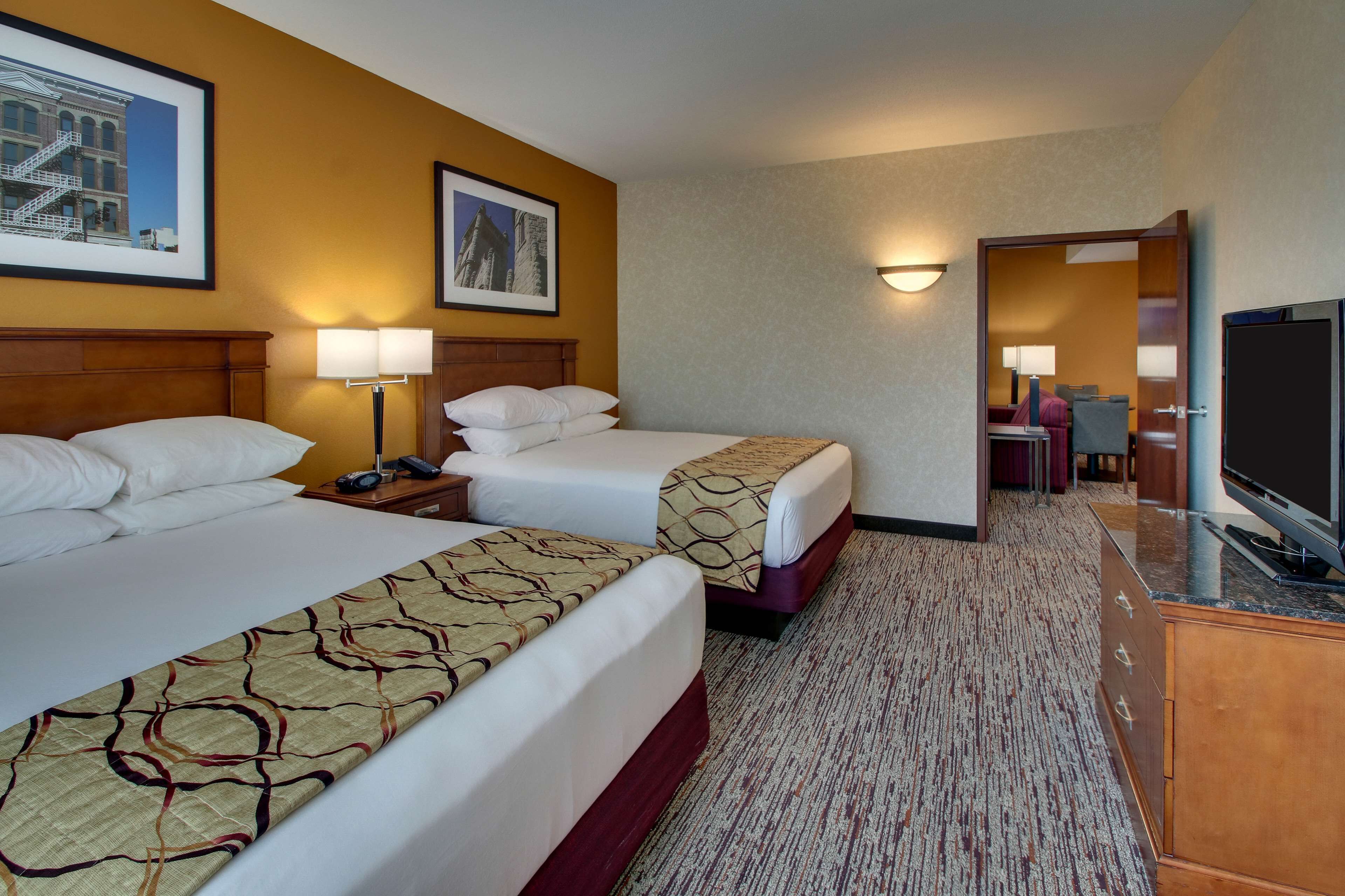 A hotel room with two beds, a television, a desk, and a chair.