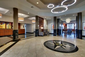 A spacious lobby with a central star design on the floor, a reception desk, seating area, and modern lighting fixtures. - Drury Inn & Suites Findlay (Findlay)
