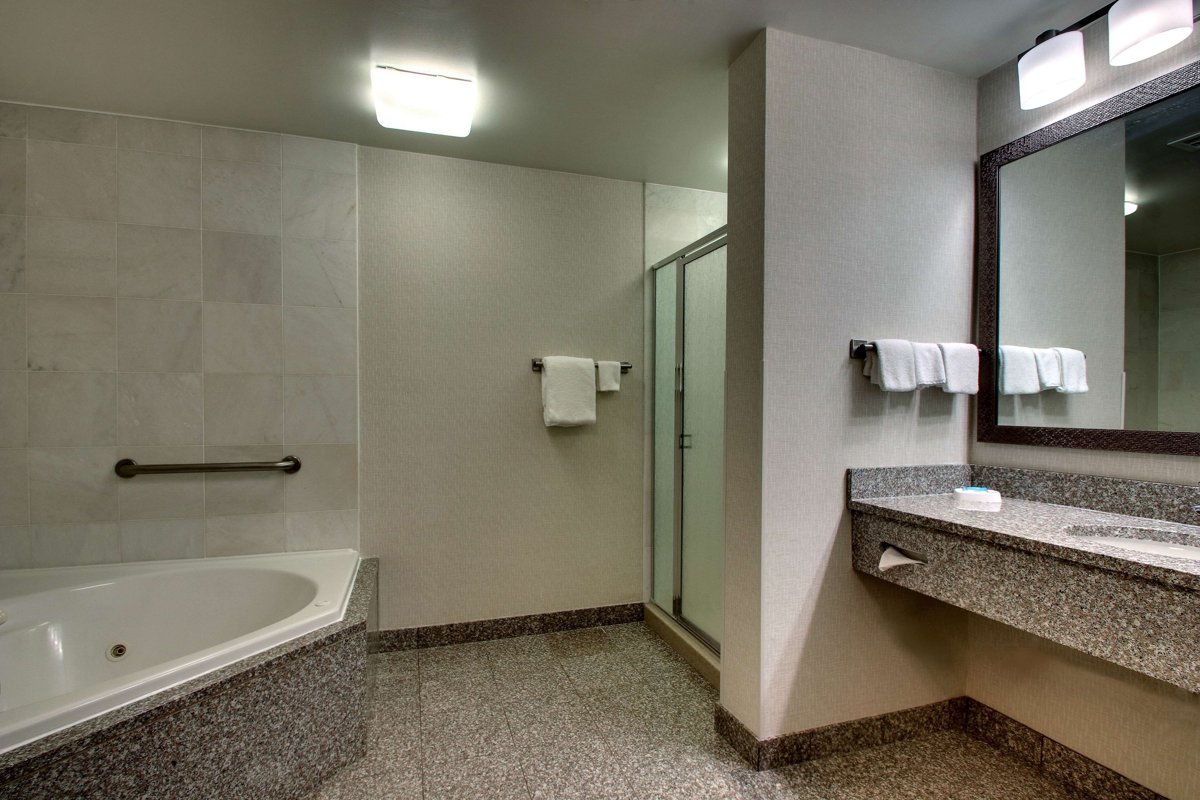 Un baño con bañera, cabina de ducha de vidrio, tocador con espejo y barandilla.