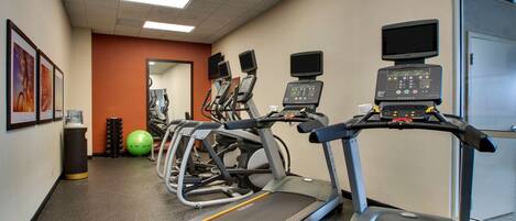 A fitness center with treadmills, elliptical machines, and exercise balls.