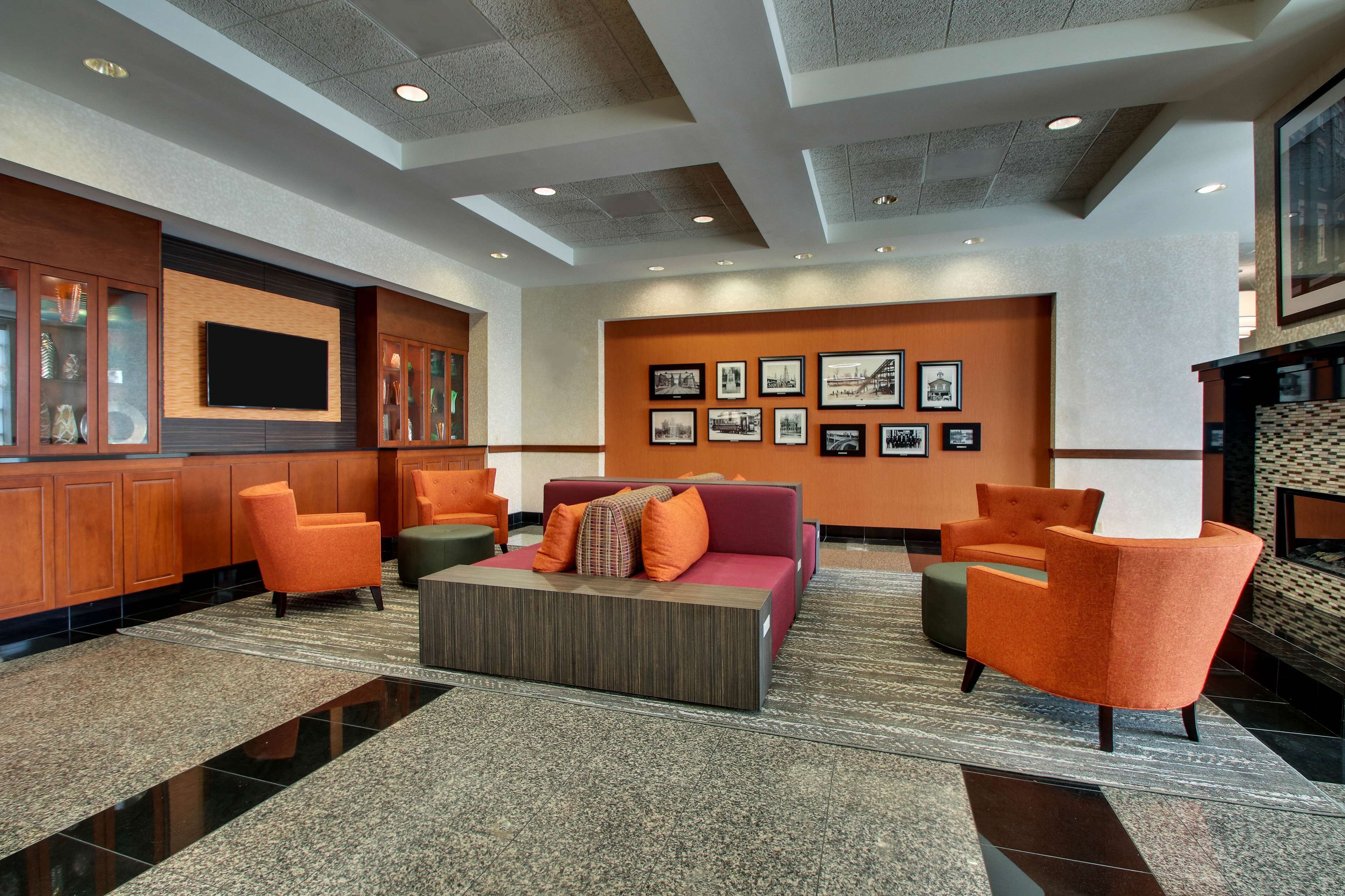 A lobby with a reception desk, seating area, and wall-mounted television.