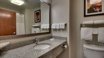 A bathroom with a granite sink, a mirror, a toilet, and a towel rack.