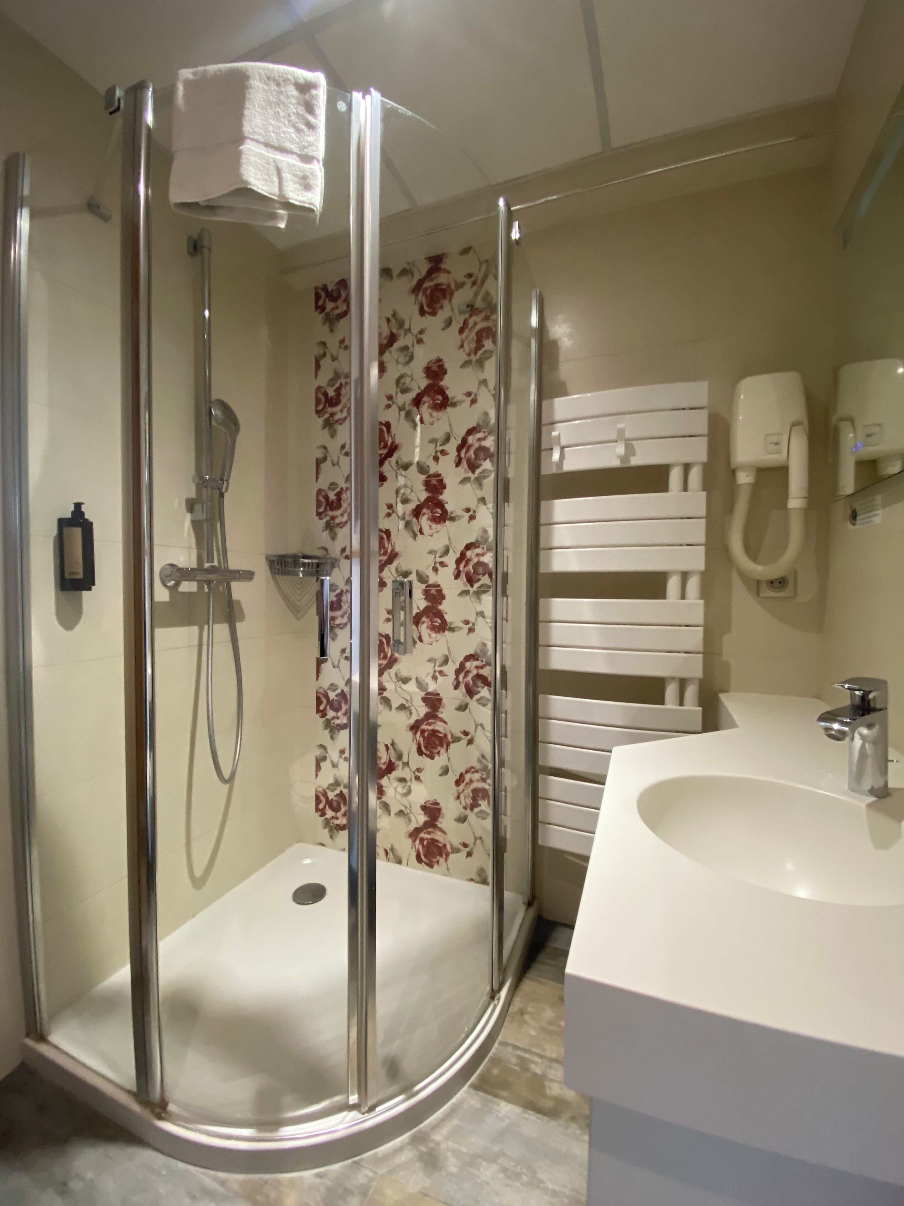 A modern bathroom with a glass-enclosed shower, a white sink, and a towel rack.