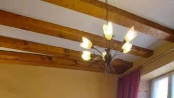 Una cama doble con cabecera de madera, una mesita de noche con lámpara, una silla y una ventana con cortinas.