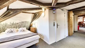 A bedroom with a bed, wooden beams, a wardrobe, and a view of trees.