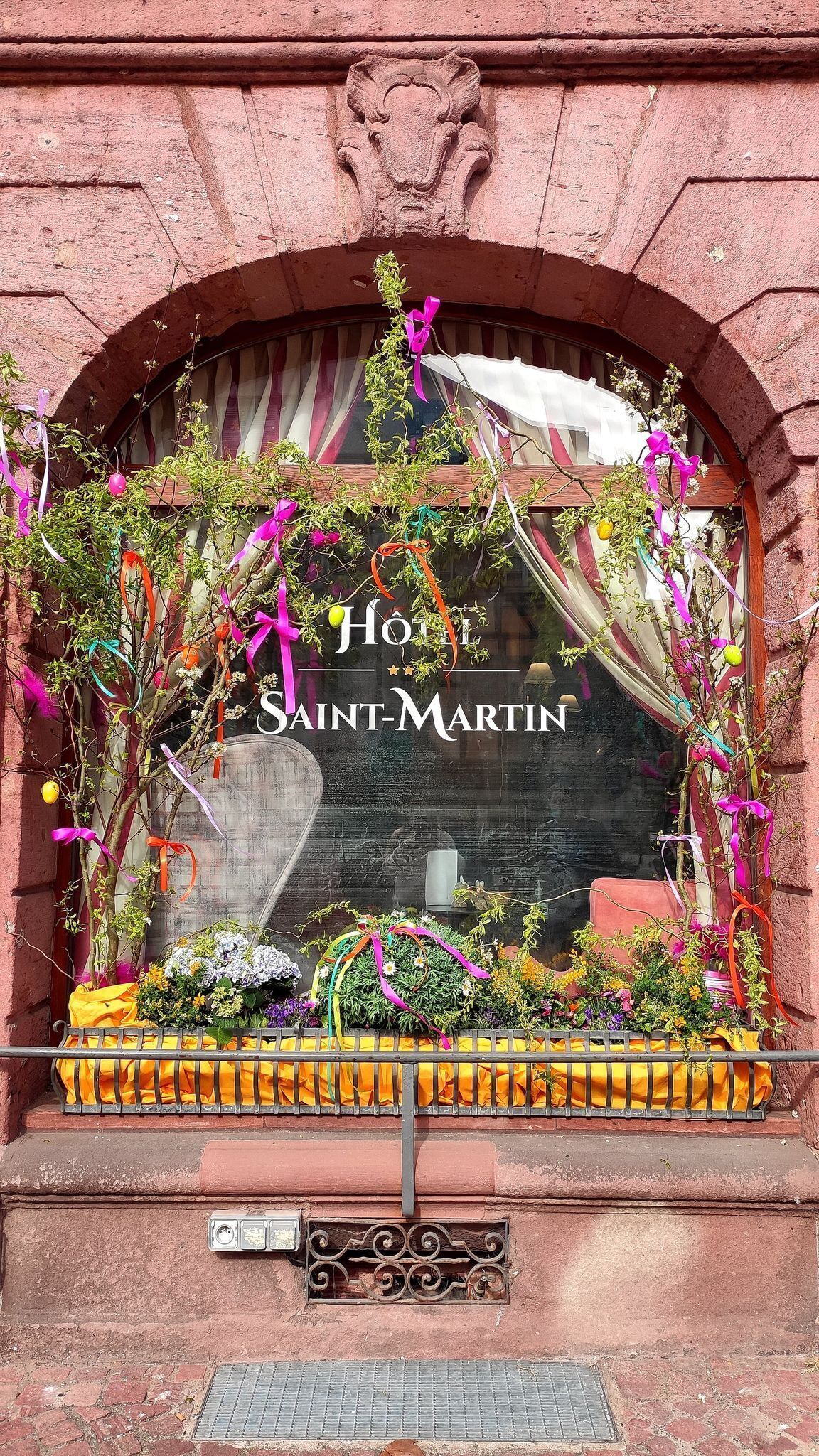 A hotel entrance with a sign reading 'Hôtel Saint-Martin' and a decorative window display.