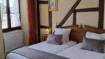 Un letto matrimoniale con testiera in legno, un comodino, un quadro incorniciato e una finestra con tende.