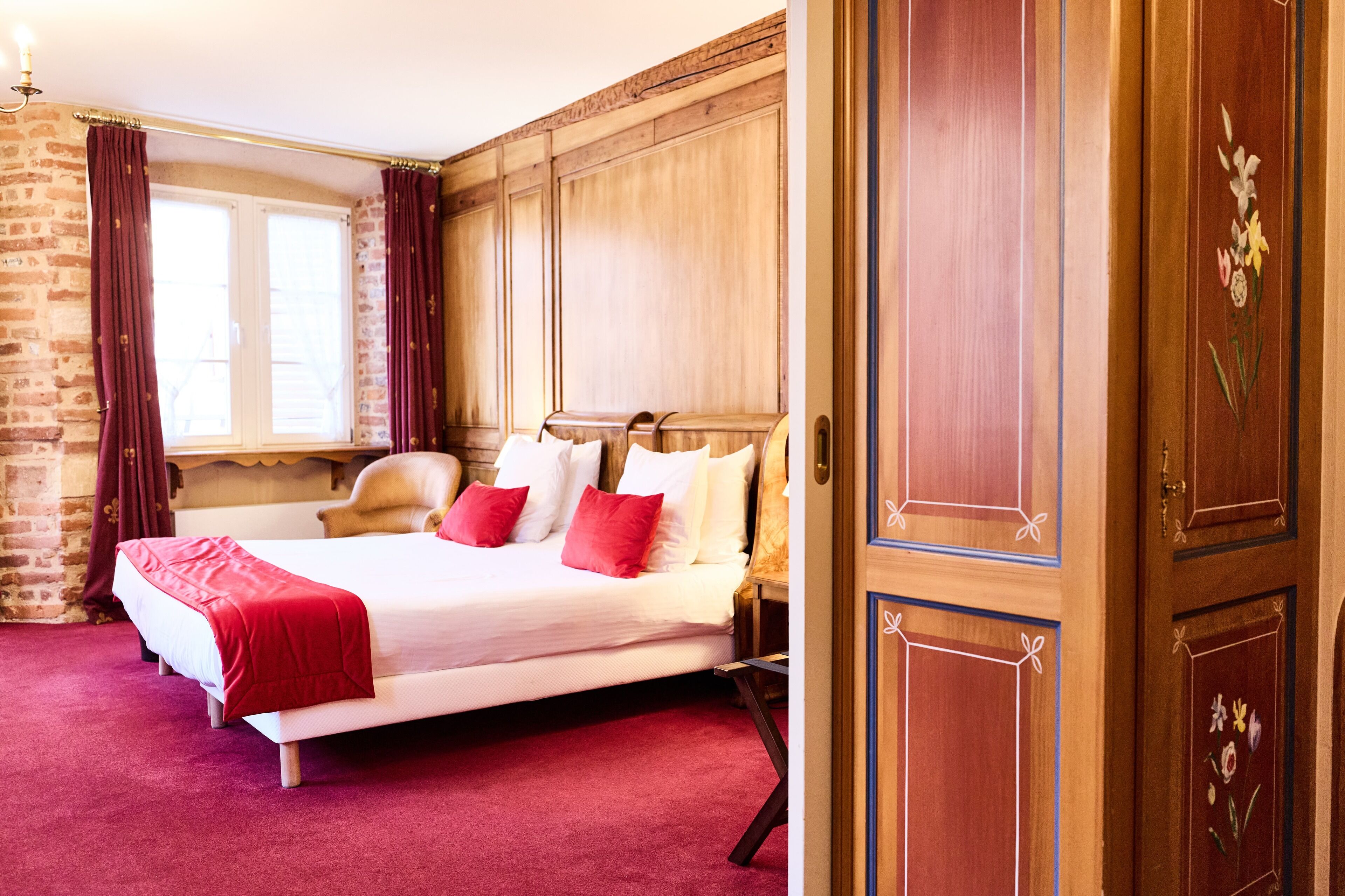Un dormitorio con una cama grande, un armario de madera y una pared de ladrillo.