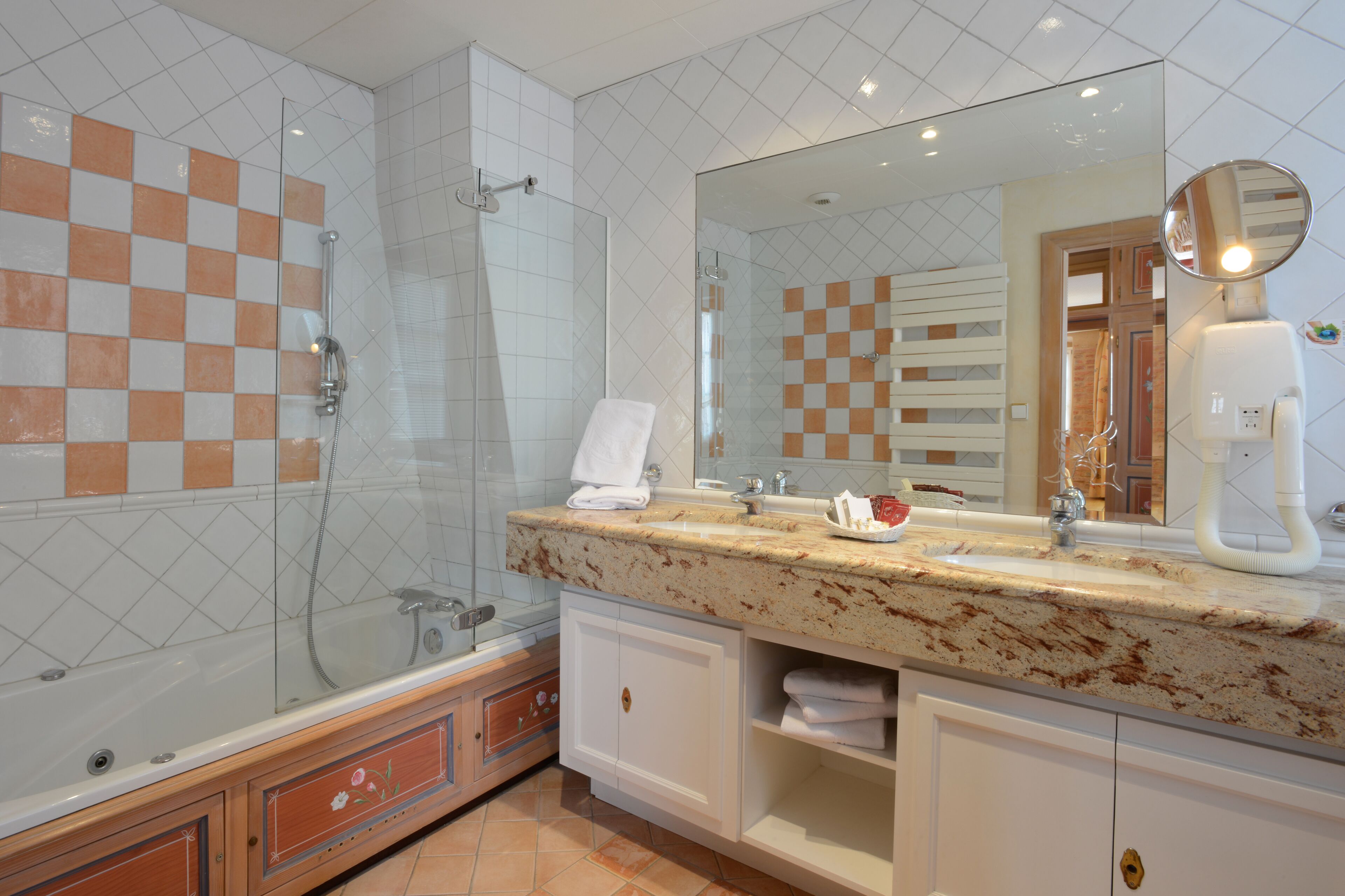A modern bathroom with a glass-enclosed shower, a large mirror, and a marble countertop.