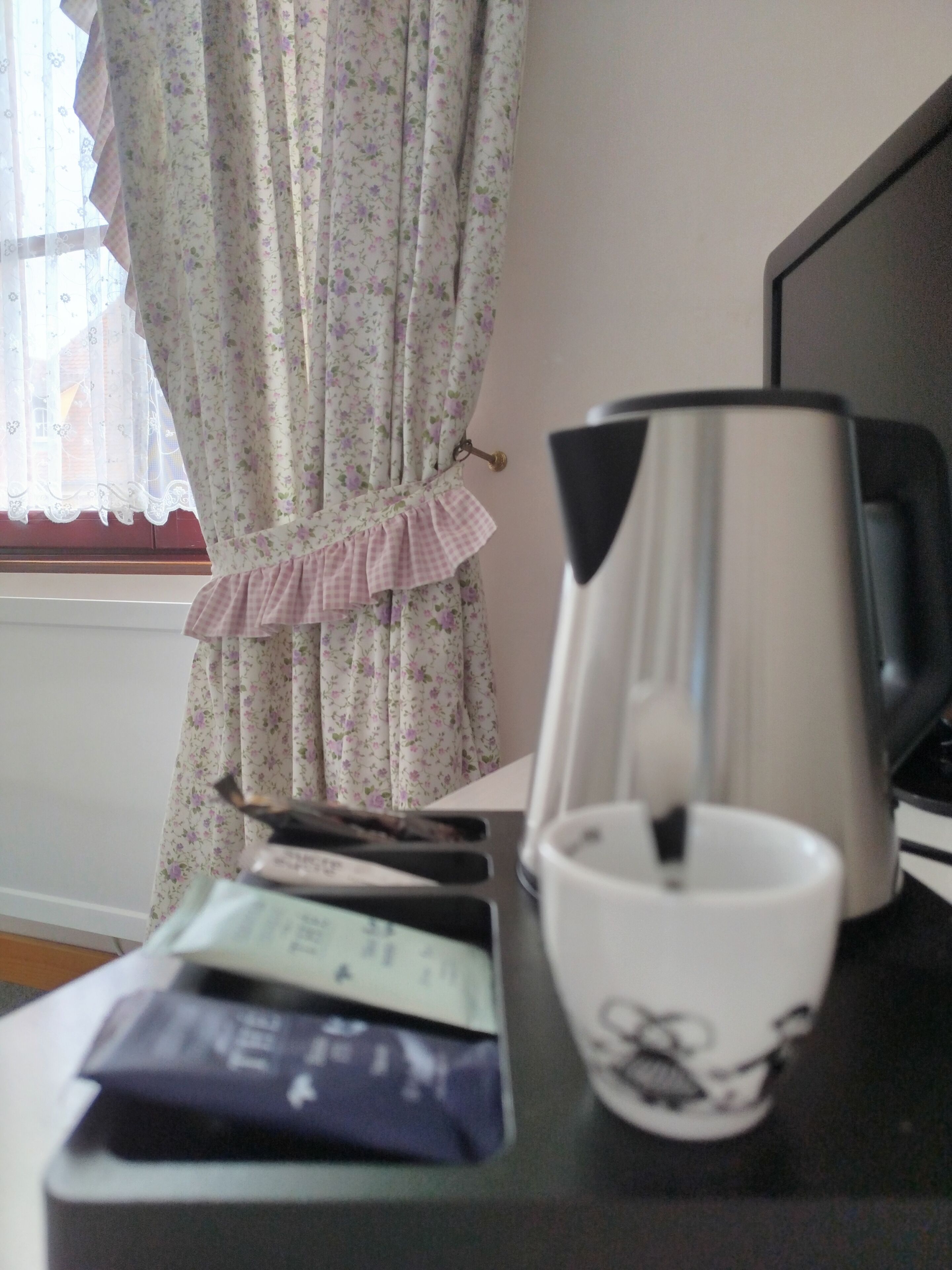 A desk with a coffee maker, a cup, and some papers.