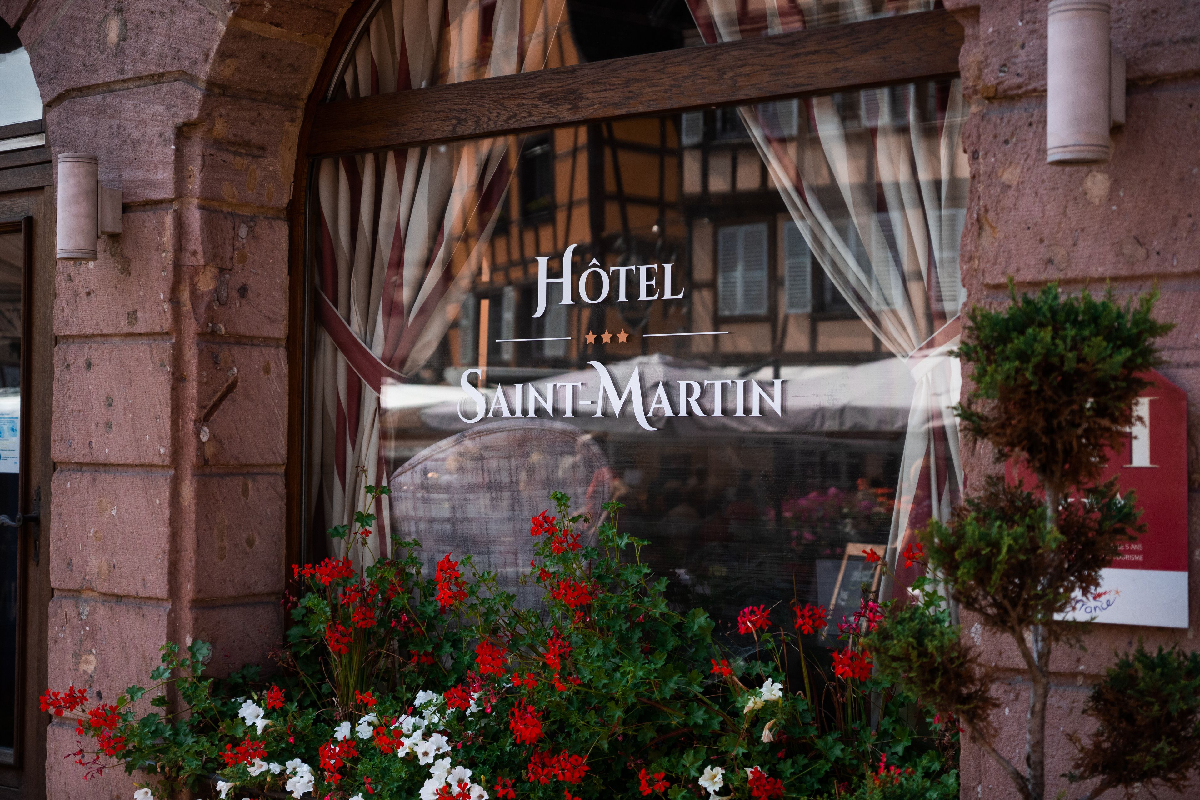 Una finestra di un hotel con la scritta "Hotel Saint-Martin" e vista sulla strada sottostante.