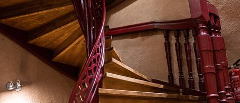 Una escalera en espiral de madera con barandilla roja y peldaños de madera.