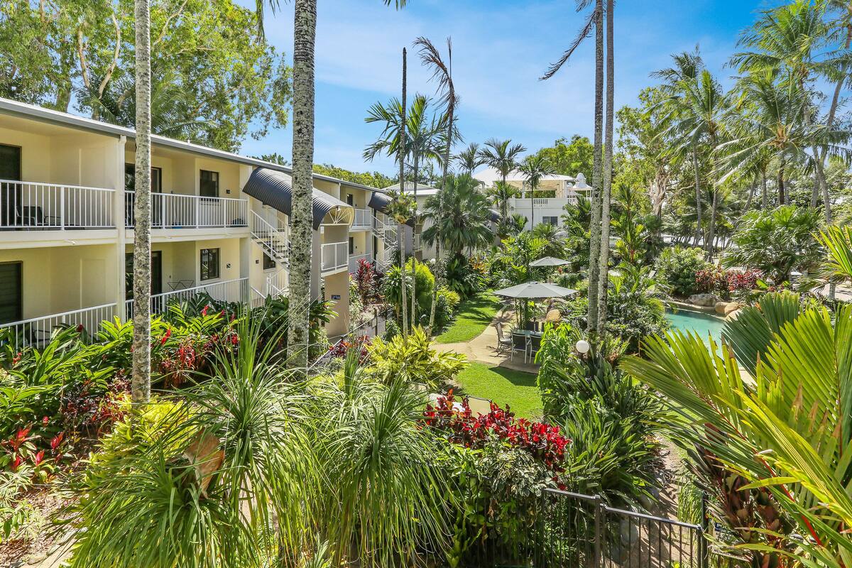 Ein Hotel mit mehreren Balkonen, einem Swimmingpool und üppiger tropischer Bepflanzung.