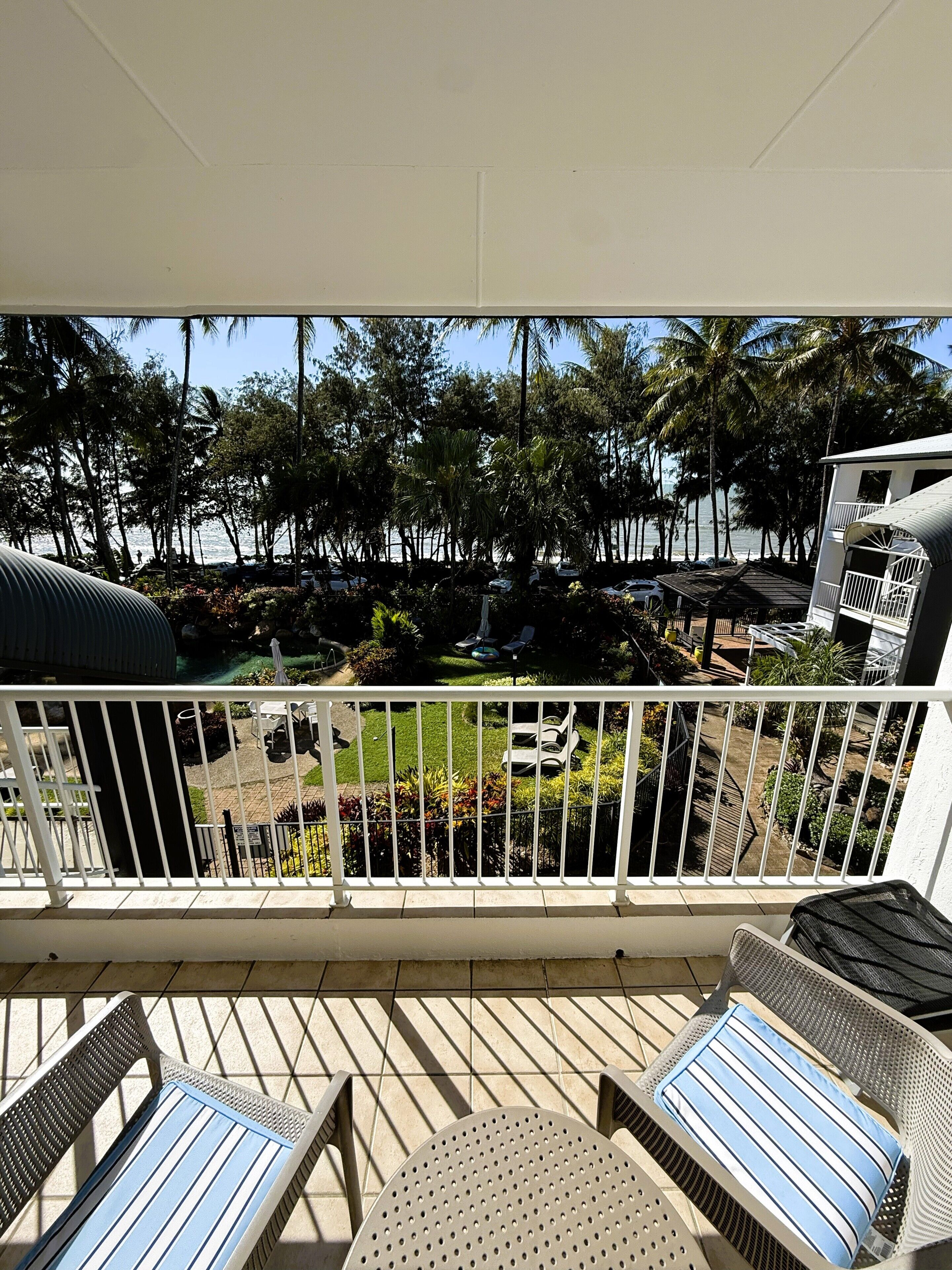 A balcony with a view of a landscaped garden and a building with a balcony.