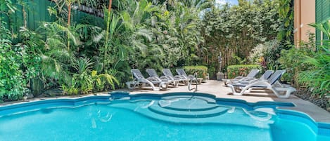 Una piscina al aire libre, sillones reclinables de piscina