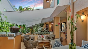 Un patio con mobiliario de mimbre, una mesa y un florero.
