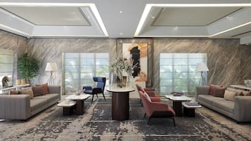 A modern lobby with a marble wall, a central table with vases, sofas, and a large window with a view of palm trees.