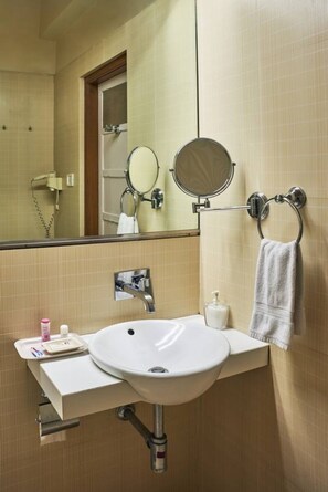 A bathroom with a sink, mirror, towel rack, and a hairdryer on the wall. - Astoria Hotel (Mumbai)