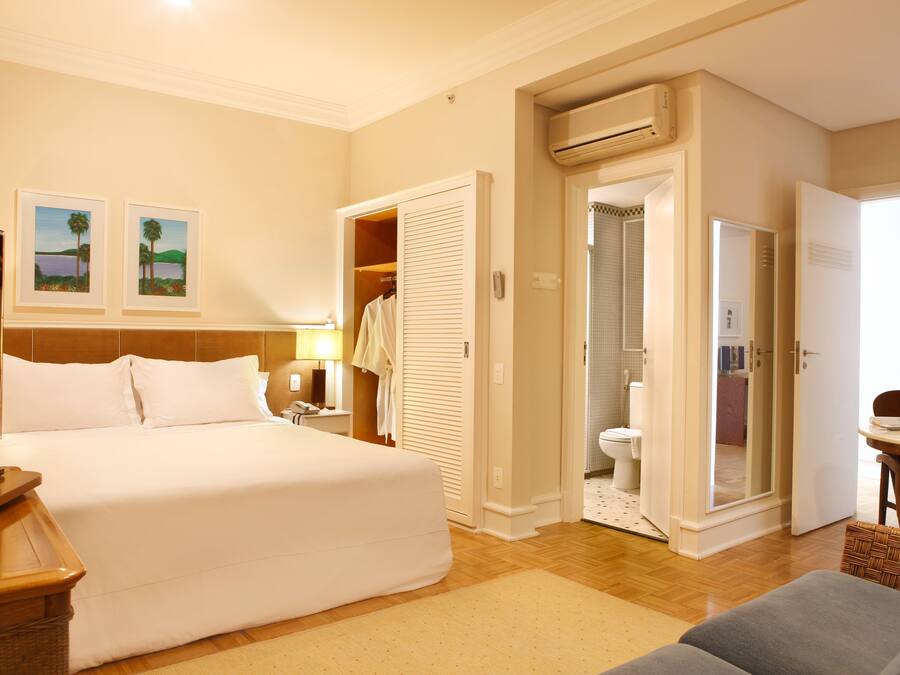 Habitación de hotel con una cama grande, un escritorio con silla, un armario y un equipo de aire acondicionado.
