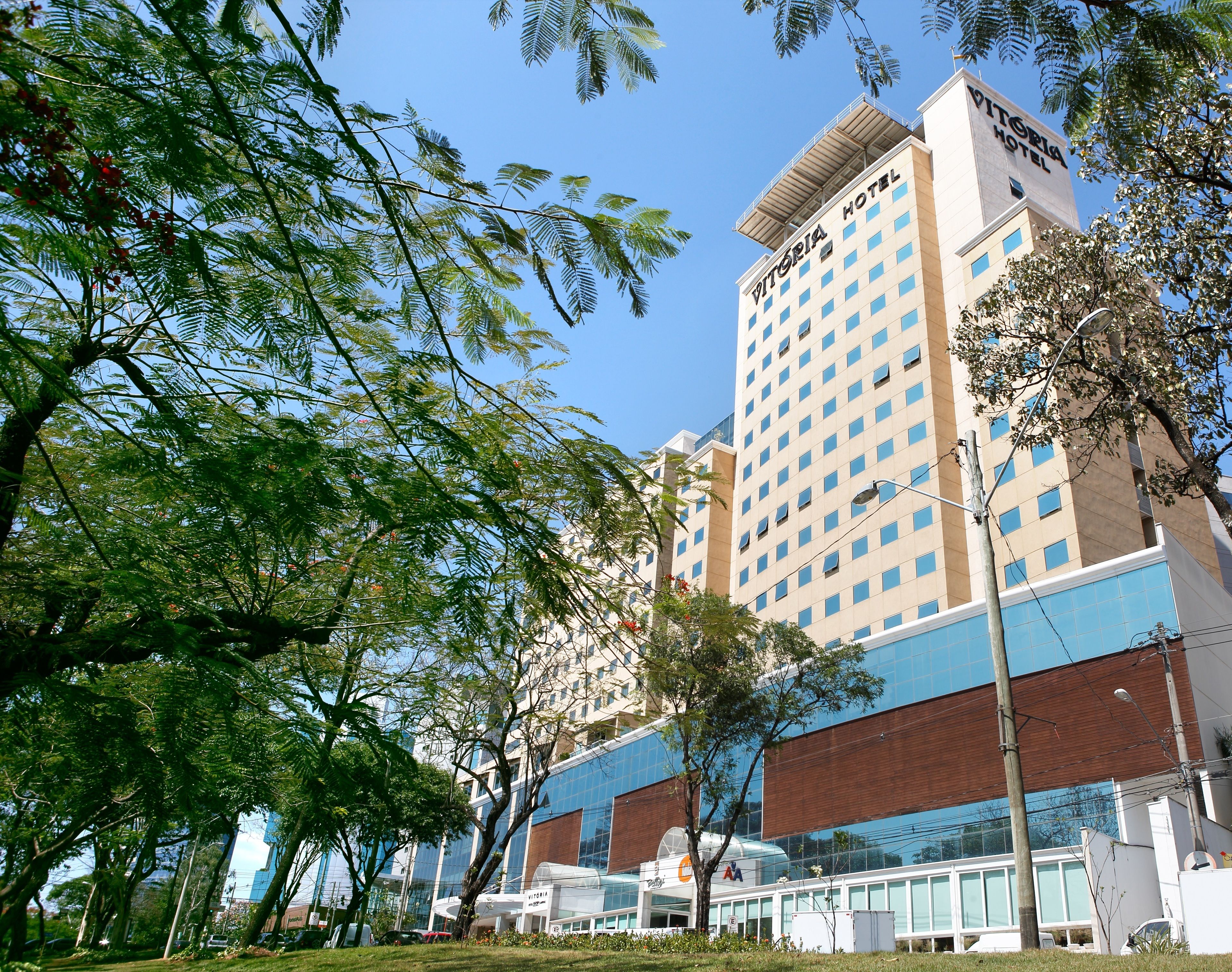 Un hotel moderno con un letrero llamativo, fachada de vidrio y césped bien cuidado.