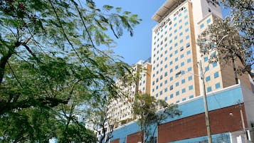 Un hotel moderno con un letrero llamativo, fachada de vidrio y césped bien cuidado.