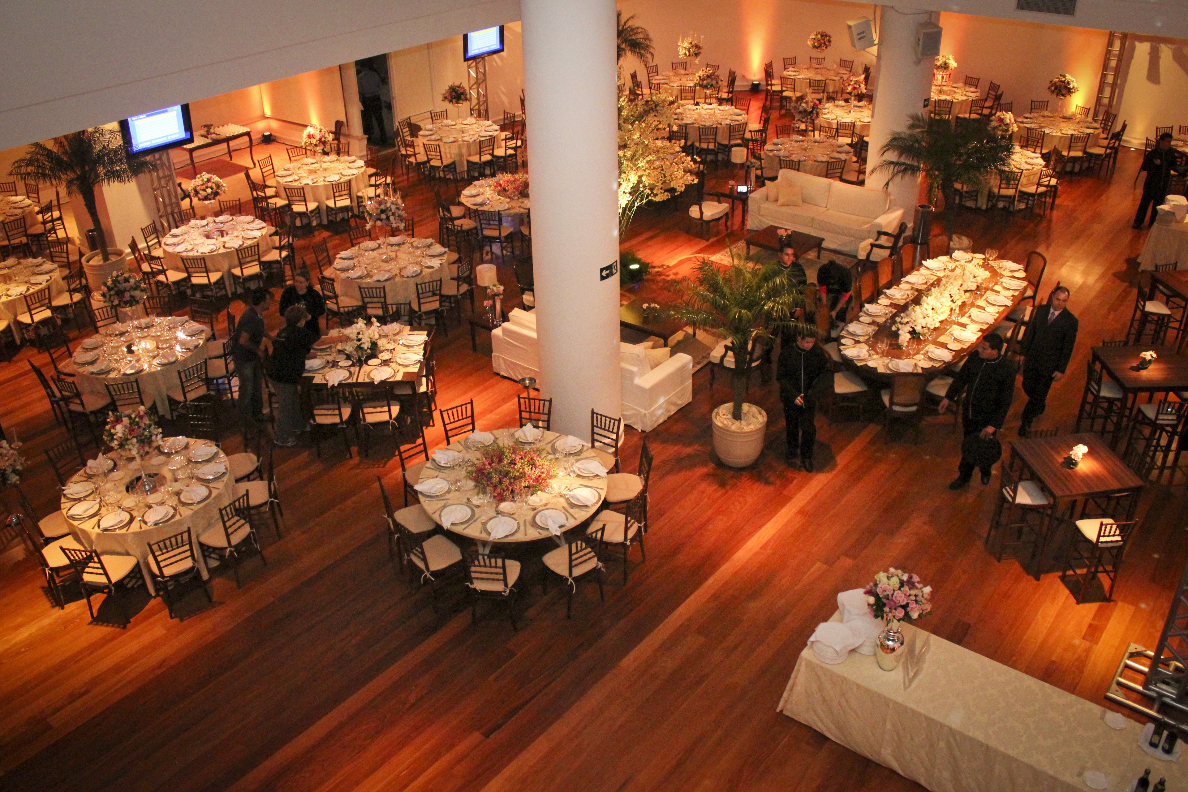 En rummelig hotelrestaurant med flere runde borde, nogle med hvide duge og blomsterarrangementer.
