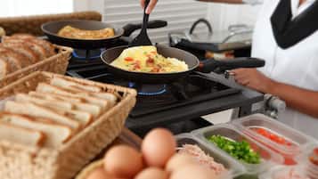 A kitchen with a frying pan on a stove, a basket of bread, and containers of ingredients.
