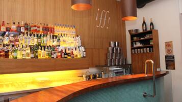 Una zona de bar con mostrador de madera, diversas botellas de licor y un revoque de azulejos.