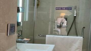 Un baño moderno con ducha acristalada, lavamanos y un perchero para toallas.