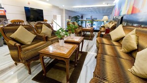 A hotel lobby with wicker furniture, a flat-screen TV, and a mural on the wall.