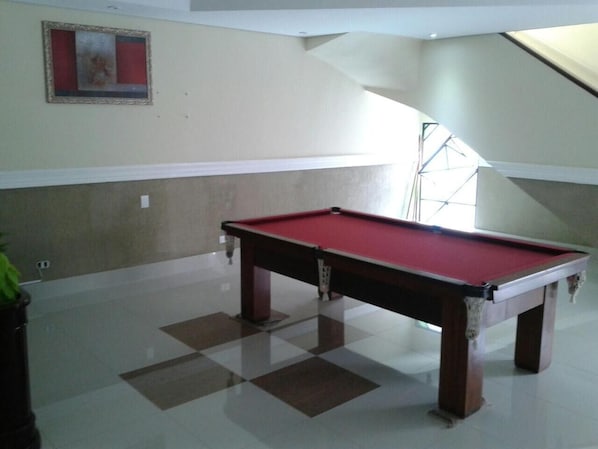 A pool table in a room with a checkered floor, a framed picture on the wall, and a staircase in the background. - Hotel Estação Express (Curitiba)