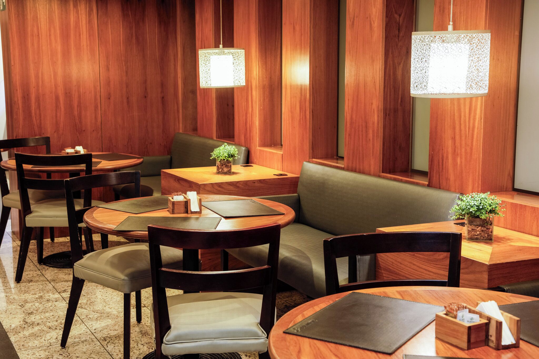 A restaurant with wooden panel walls, round tables, and cushioned seating.