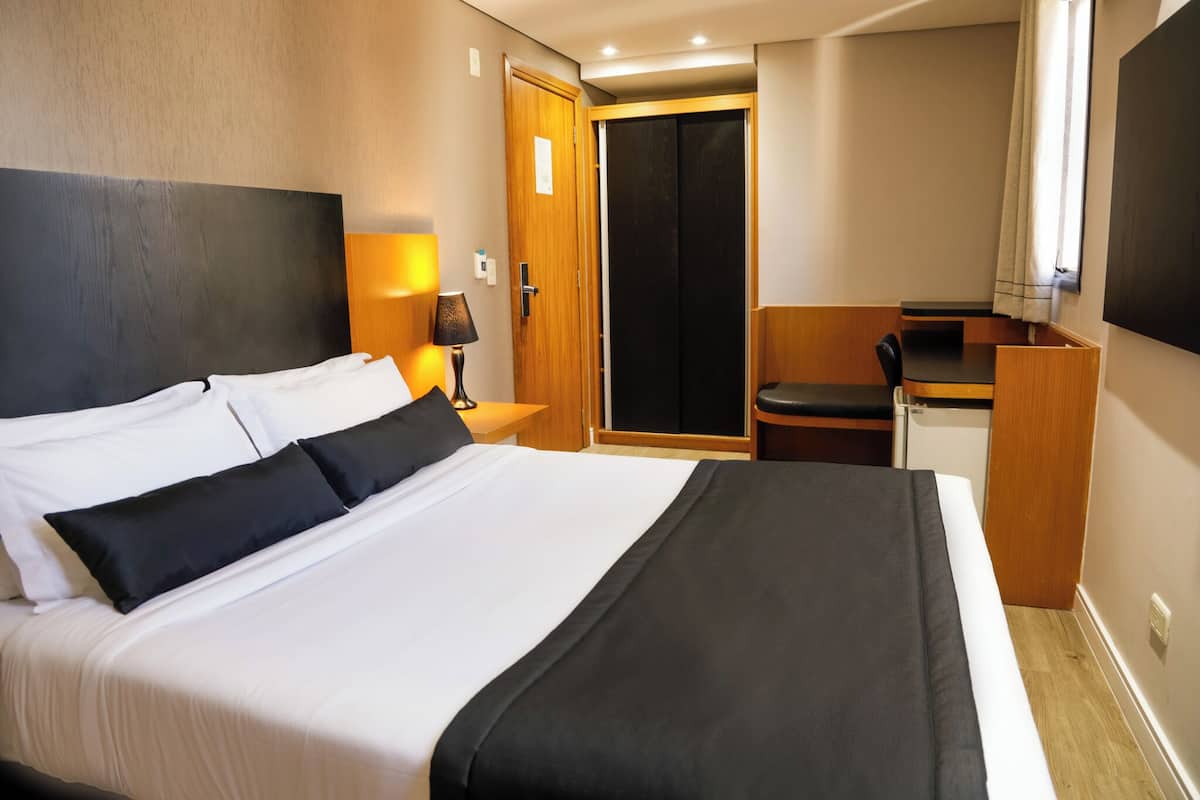 Una habitación de hotel con una cama grande, un escritorio y una silla.