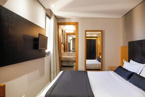 A hotel room with a large bed, a bedside table, a TV mounted on the wall, and a bathroom visible through an open door. - SLAVIERO Curitiba Batel (Curitiba)