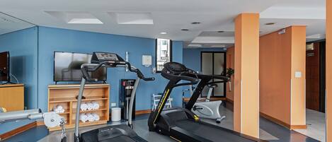 Un gimnasio con cintas de correr, una bicicleta estática y una máquina de remo.