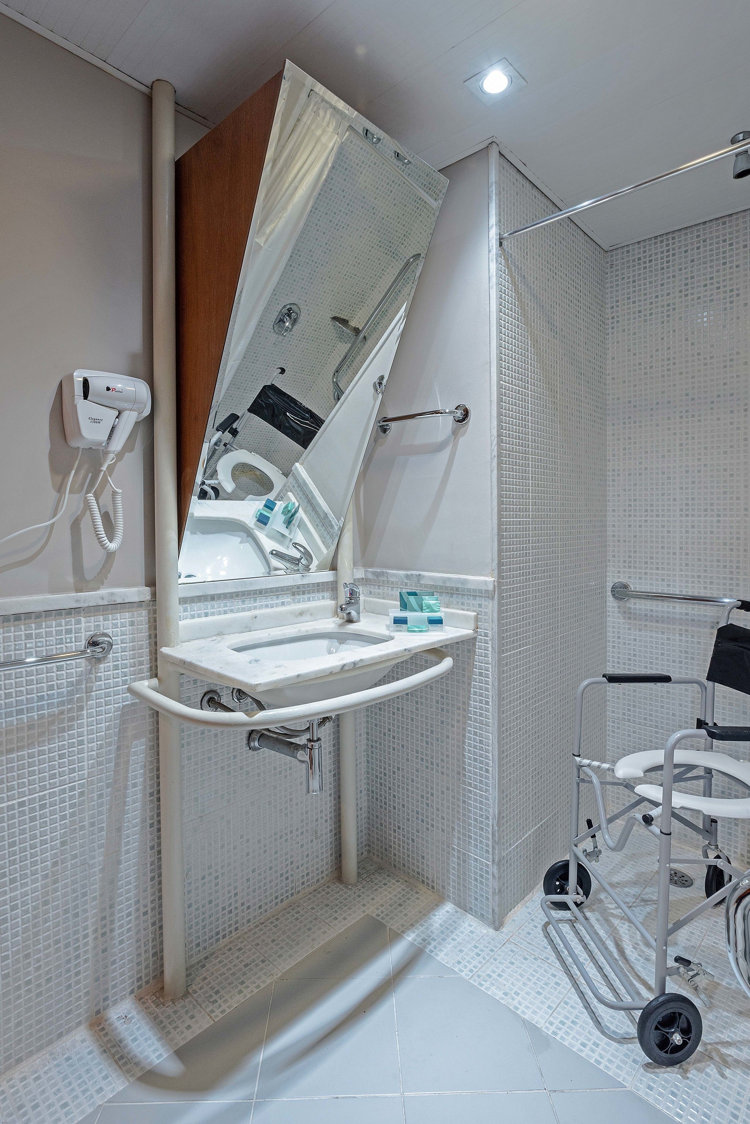 Un baño moderno con ducha, lavamanos y asiento de ducha accesible para sillas de ruedas.