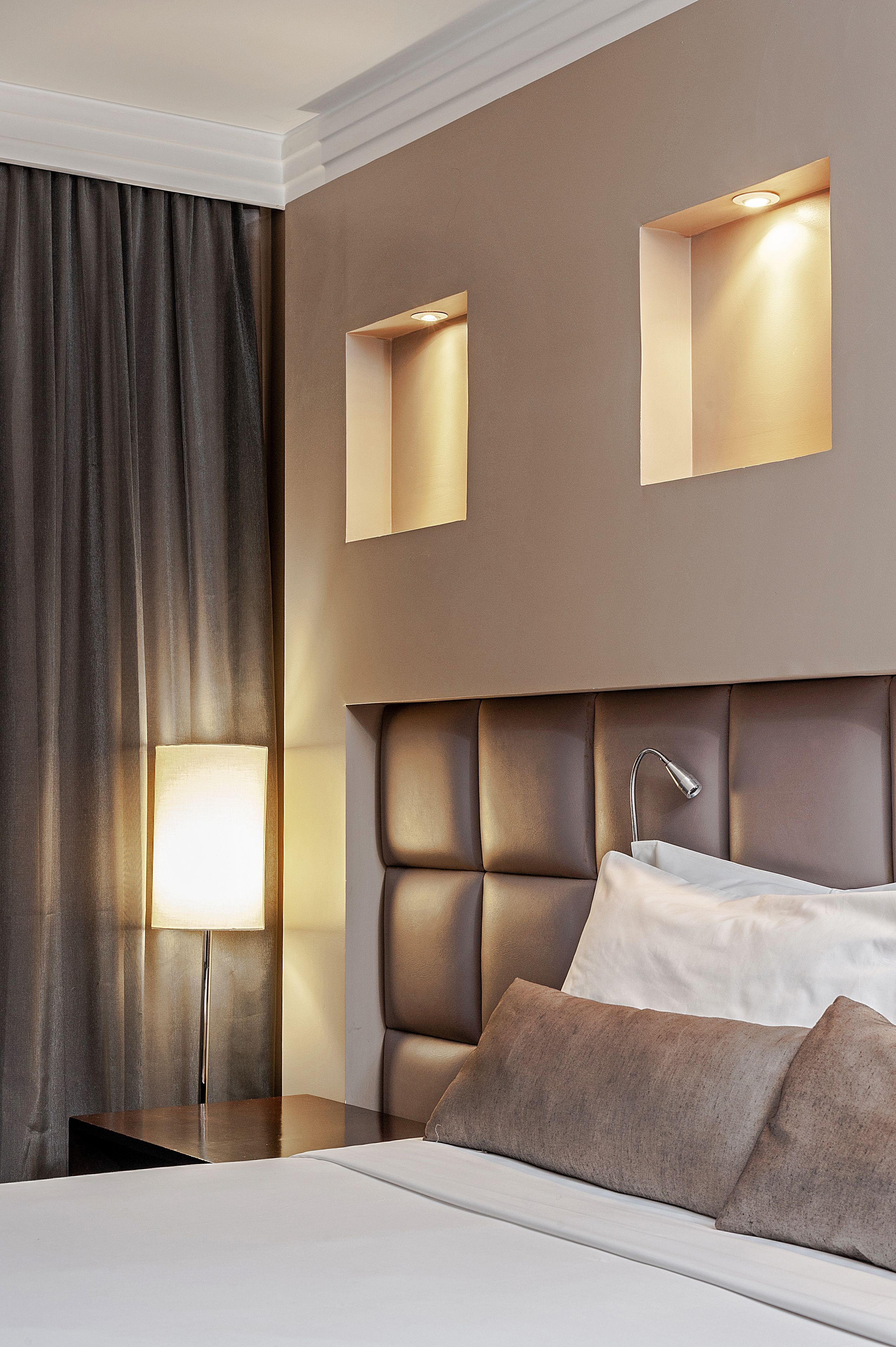 Een moderne hotelkamer met een groot bed, een nachtkastje met een lamp en twee wandlampen.