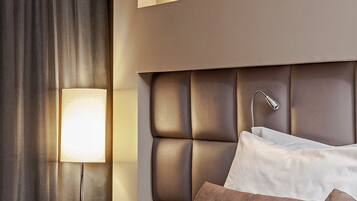 Een moderne hotelkamer met een groot bed, een nachtkastje met een lamp en twee wandlampen.