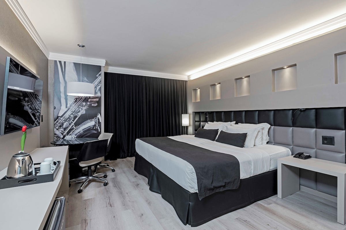 Una habitación de hotel moderna con una cama grande, un escritorio, una silla y un televisor de pantalla plana.
