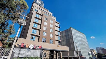 A hotel with multiple floors, a prominent sign for 'All Jazz Hotel', and a modern glass building adjacent to it.